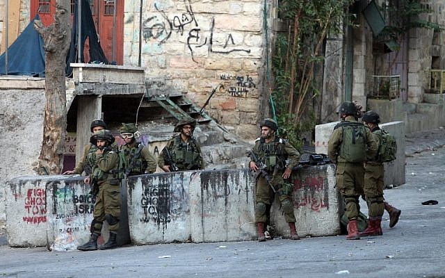 IDF soldiers stand guard near the site where a Palestinian attempted to stab a soldier before being shot dead in the West Bank city of Hebron on October 28, 2015. (AFP Photo/Hazem Bader)