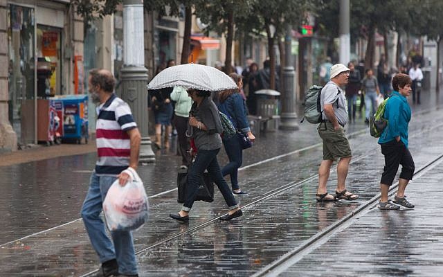 People hold umbrellas to protect themselves from the rain as they walk on Jaffa street, downtown Jerusalem, during the first rain of the upcoming winter, October 7, 2015. (Photo by Yonatan Sindel / Flash90)