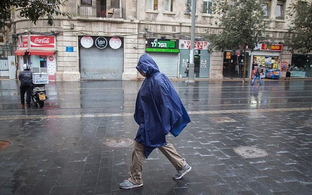 A man walks with a rain cover to protect himself from the rain as he walks on Jaffa street, downtown Jerusalem, during the first rain of the upcoming winter, October 7, 2015. (Photo by Yonatan Sindel / Flash90)