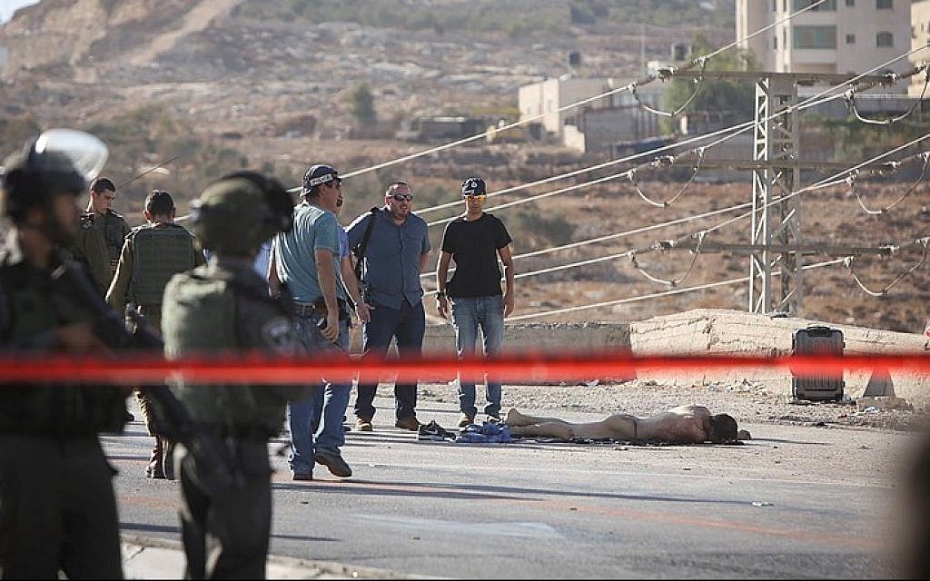Israeli security forces seen near the body of the Palestinian terrorist after he stabbed and severely wounded an Israeli soldier near the Adam junction, north of Jerusalem. The stabber was shot and killed by security forces at the scene, the IDF said. October 21, 2015. (Yonatan Sindel/FLASH90)