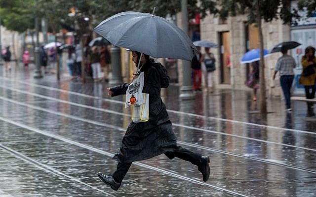 An ultra-Orthodox Jewish man holds an umbrella on Jaffa Street, downtown Jerusalem on a rainy day, October 25, 2015. (Yonatan Sindel/Flash90) 