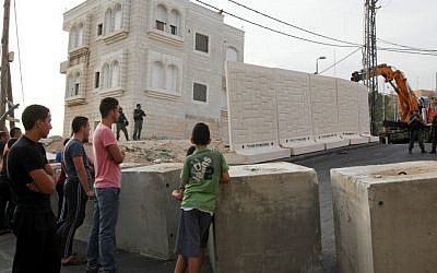 Palestinians watch a wall being built between Palestinian and Jewish neighborhoods in Jerusalem Sunday, Oct. 18, 2015. (AP Photo/Mahmoud Illean)