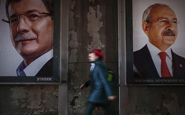 In this Tuesday, Oct. 27, 2015, photo a woman walks past election banners with pictures of Turkey's main opposition Republican People's Party leader Kemal Kilicdaroglu, left, and Turkish Prime Minister Ahmet Davutoglu, the leader of the Justice and Development Party (AKP), in Istanbul. (AP Photo/Emrah Gurel)