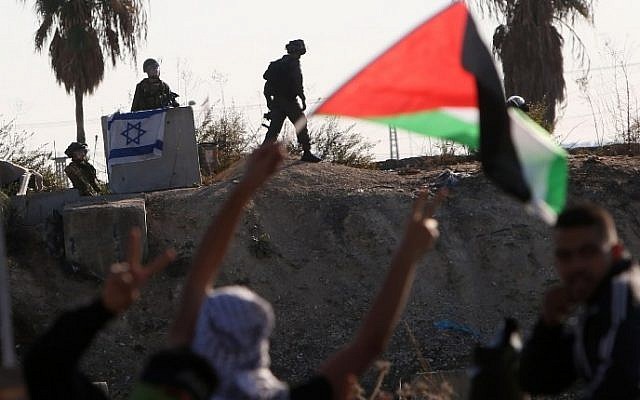 Palestinian protesters wave their national flag during clashes with members of the Israeli security forces in the West Bank city of Tulkarem on November 12, 2015. (Jaafar Ashtiyeh/AFP)