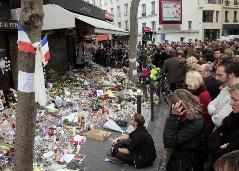 People observe a minute of silence on November 16, 2015 outside the La Belle Equipe on Rue de Charonne in the XI arrondissements in Paris, to pay tribute to victims of the attacks claimed by Islamic State which killed at least 129 people and left more than 350 injured on November 13. (AFP PHOTO/JACQUES DEMARTHON)