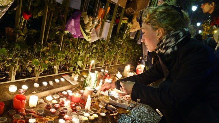 A woman lights candles at a makeshift memorial next to the Bataclan concert hall on November 16, 2015 in Paris. (AFP/ BERTRAND GUAY)
