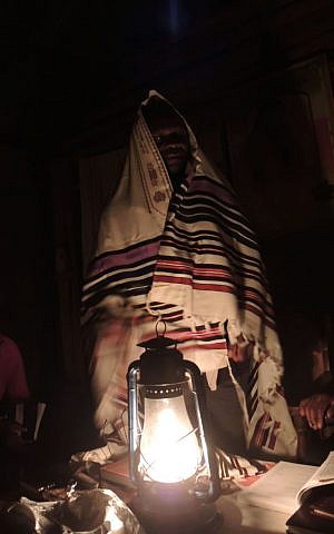 Yosef Njogu tries on a donated tallit, or prayer shawl. (Melanie Lidman/Times of Israel)