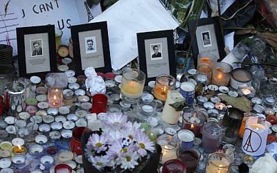 Pictures of victims are placed behind candles outside the Bataclan concert hall in Paris, Sunday, Nov. 15, 2015. (AP Photo/Christoph Ena)