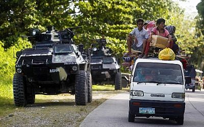 People drive past an armoured personnel carrier (APC) in Kauran, Ampatuan in the southern Philippines province of Maguindanao on December 24, 2015. (AFP PHOTO/MARK NAVALES)