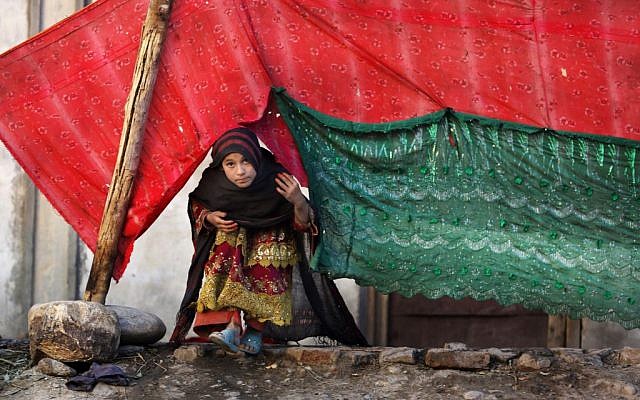 In this Nov. 29, 2015 photo, an internally displaced girl peeks from a tent after her family left their village in Rodat district of Jalalabad, Afghanistan. Nangarhar’s chief refugee official says that at least 25,200 families, or more than 170,000 people, have been displaced across the province, either by Islamic State or perceived threats from the group. (AP Photo/Rahmat Gul)