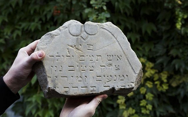 In this picture taken on Monday Oct. 26, 2015, Tomas Jelinek displays part of a tombstone in efforts to restore a former Jewish cemetery in Prostejov, Czech Republic. (AP Photo/Petr Josek)