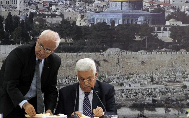 PA President Mahmoud Abbas (R) and chief peace negotiator Saeb Erekat sign an application to join UN agencies, in the West Bank city of Ramallah, on Tuesday, April 1, 2014. (Issam Rimawi/Flash90)