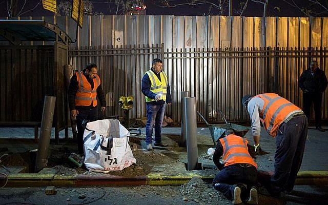 Israeli and Palestinian laborers place barriers at a bus stop in Jerusalem on December 20, 2015, after a terror attack there last week. (Yonatan Sindel/Flash90)