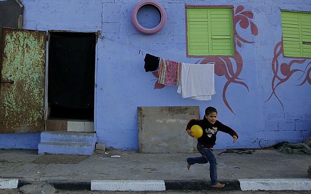 In this Saturday Dec. 19, 2015 photo, a Palestinian boy runs by a painted house in the Shati Refugee Camp in Gaza City. (AP Photo/Hatem Moussa)