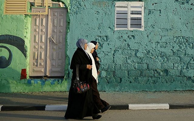 In this Saturday Dec. 19, 2015 photo, Palestinians walk past a painted house in the Shati refugee camp in Gaza City. (AP Photo/Hatem Moussa)