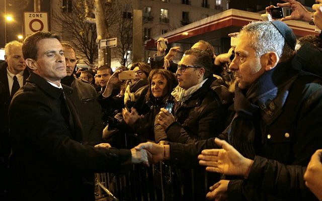 Manuel Valls (L) shakes hands with people on January 9, 2016 near the Hyper Cacher, a kosher supermarket, during a ceremony to pay tribute to the victims of the attack on the supermarket on January 9, 2015. (Jacques Demarthon/Pool/AFP)