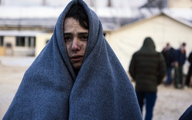 A migrant wrapped in a blanket to keep warm waits at a registration camp in southern Serbian town of Presevo on January 22, 2016, after crossing the Macedonian border. (AFP / DIMITAR DILKOFF)