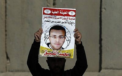 Photo taken on January 22, 2016, shows a Palestinian man carrying a placard bearing a portrait of Palestinian journalist Mohammed al-Qiq during a demonstration near Ramallah demanding his release from an Israeli jail. (Abbas Momani/AFP, File)