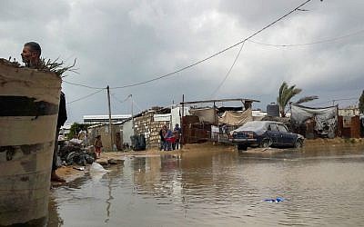 Palestinians stand near a road flooded with rainwater following heavy rains, in Khan Younis in the southern Gaza Strip on January 24, 2016. (Abed Rahim Khatib/Flash90)