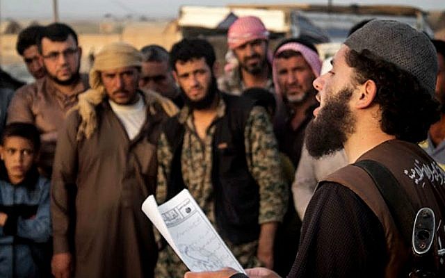 In this file photo released on May 14, 2015, by a militant website, a member of the Islamic State group's vice police known as 'Hisba' reads a verdict handed down by an Islamic court in Raqqa, Syria, sentencing many they accused of adultery to lashing (Militant website via AP, File)