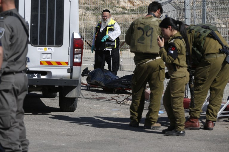 A Zaka volunteer and Israeli security forces stand next to the body of a Palestinian assailant shot dead following an attempt to stab border police at a checkpoint near Har Homa in the West Bank on February 14, 2016. (AFP/AHMAD GHARABLI)