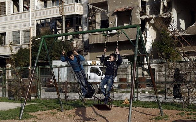 Syrian children play on a swing at a park in the rebel-held town of Douma, on the eastern edges of the capital Damascus on February 27, 2016. (AFP / Sameer Al-Doumy)
