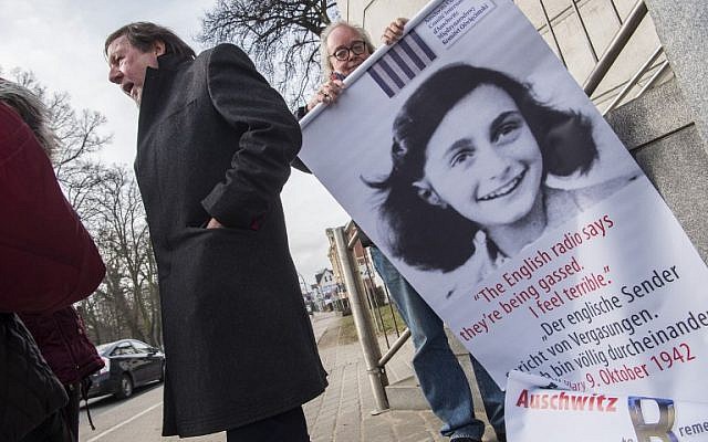 An activist with the Inernational Auschwitz Committee rolls up a poster featuring Holocaust victim Anne Frank outside the regional court of Neubrandenburg during the first day of the trial against former SS medic Hubert Zafke, accused of aiding in 3,681 murders in Auschwitz in 1944, on February 29, 2016. (AFP/John MACDOUGALL)