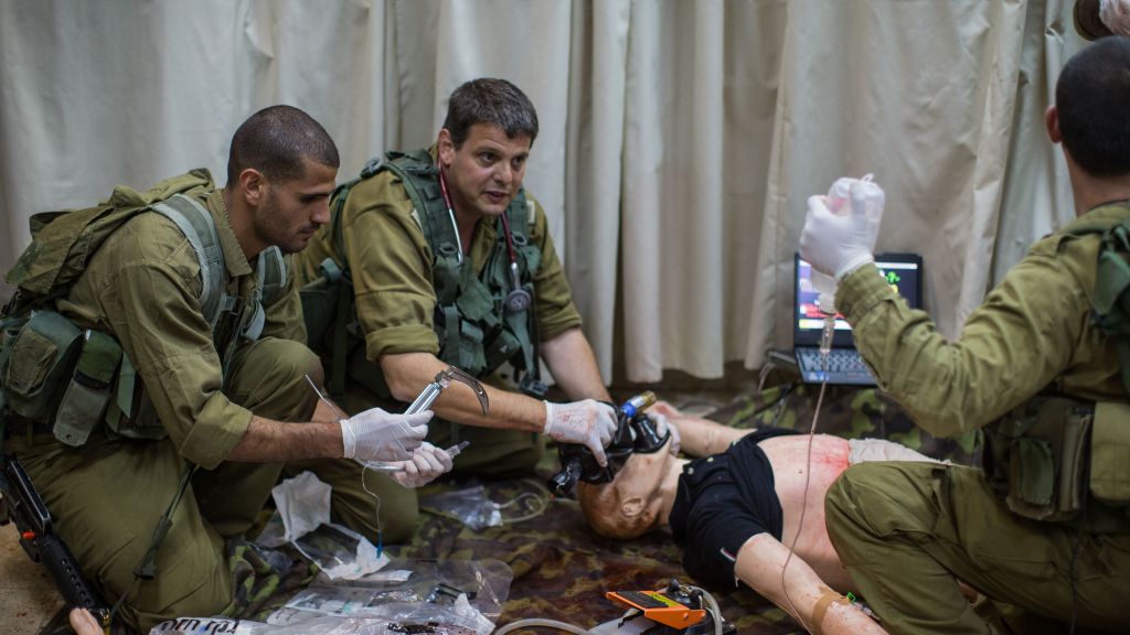 Dr. Amit Alfassi, center, treats a 'patient,' a smart doll that mimics the human respiratory and circulatory systems, in the Medical Simulation Center at Tel Hashomer Hospital in Ramat Gan on February 11, 2016. (Adi Brown/IDF Spokesperson's Unit)
