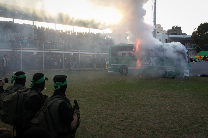 Palestinian militants of the Izz ad-Din al-Qassam, the armed wing of Hamas, burn a fake Israeli bus during an anti-Israel rally in the southern Gaza Strip city of Rafah on February 26, 2016. (Abed Rahim Khatib/Flash90)