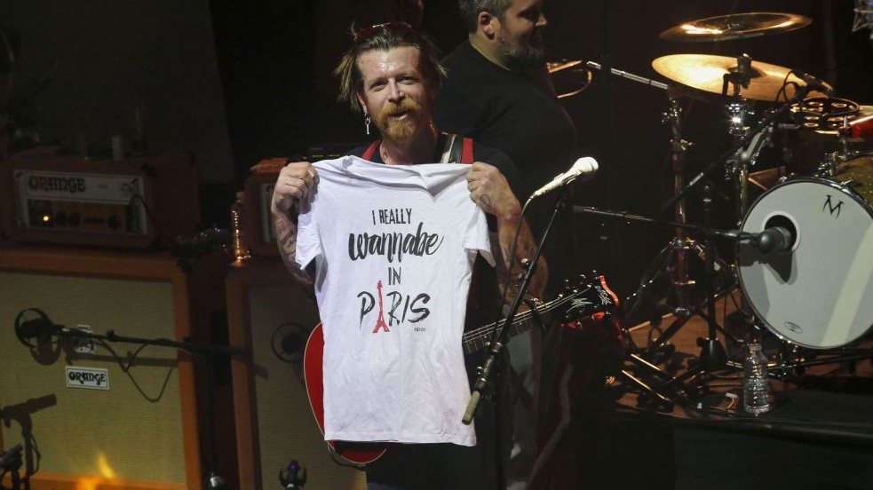 Eagles of Death Metal frontman Jesse Hughes holds a T-shirt with slogan, "I really wanna'be in Paris" as the rock band performs Tuesday Feb. 16, 2016, at the Olympia concert hall in Paris, France (Jean-Nicolas Guillo/Le Parisien via AP)