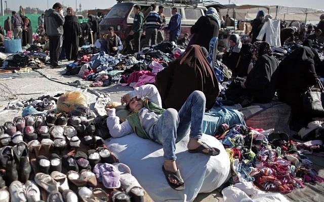 In this Monday, Feb. 15, 2016 photo, a Palestinian boy lays next to displayed used shoes for sale at the weekly flea market in Nusseirat refugee camp, central Gaza Strip. (AP Photo/Khalil Hamra) 