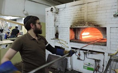 A man baking matzah in a brick oven in Kfar Chabad, a village that provides ritual materials to Chabad emissaries across Israel. (Ben Sales)
