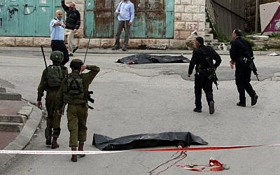 Israeli soldiers and police surround the bodies of two Palestinians who were killed after wounding an Israeli soldier in a knife attack, an army spokeswoman said, at the entrance to the heavily guarded Jewish settler enclave of Tel Rumeida in the center of the West Bank city of Hebron on March 24, 2016. (AFP / HAZEM BADER)