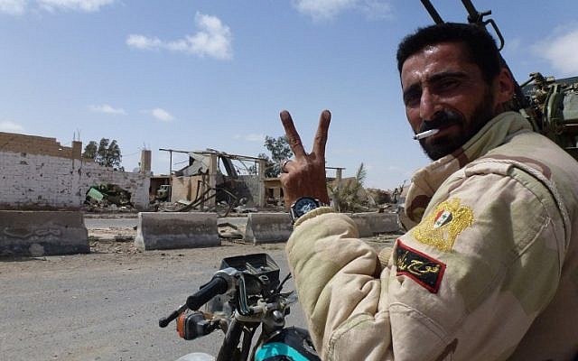 A member of the Syrian pro-government forces flashes the V-sign in a residential neighbourhood of the modern town of Palmyra on March 27, 2016, after troops recaptured the city from Islamic State. (AFP/Maher Al Mounes)