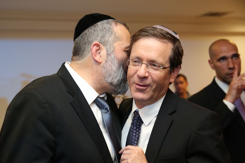 Aryeh Deri, left, whispering to Isaac Herzog at a party in Jerusalem on December 23, 2015. (Yaacov Cohen/FLASH90)