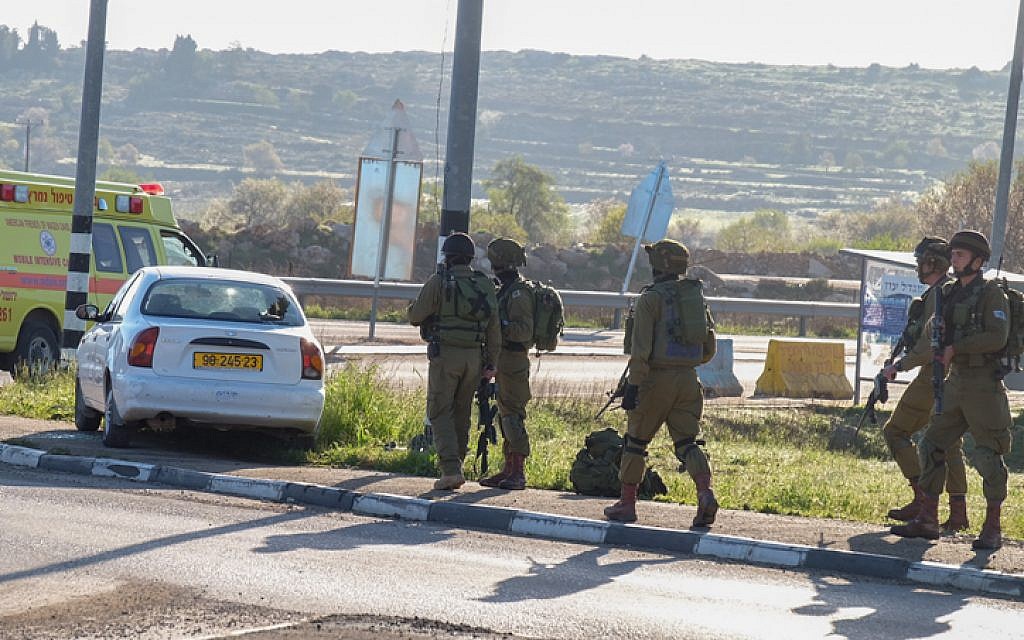 Israeli security forces approach the car of a Palestinian attacker at the scene of a car-ramming attack near the Gush Etzion Junction in the West Bank on March 4, 2016. (Gershon Elinson/Flash90)