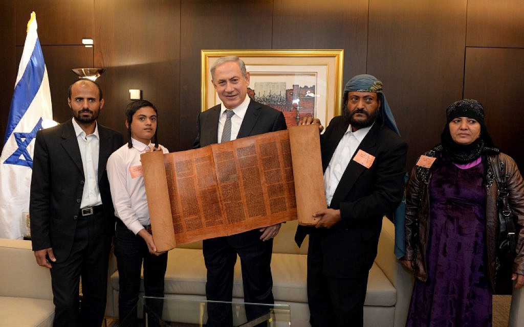 Prime Minister Benjamin Netanyahu holds an 500 hundred-year-old Torah scroll as he poses for a picture with some of the Yemenite Jews who were brought to Israel as part of a secret rescue operation, at the Knesset on March 21, 2016. (Haim Zach/GPO)