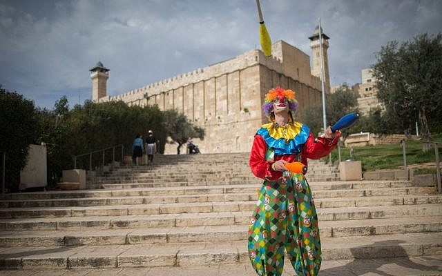 A man in a clown costume juggles during the annual parade marking the Jewish holiday of Purim in the West Bank town of Hebron on March 24, 2016. (Yonatan Sindel/Flash90)