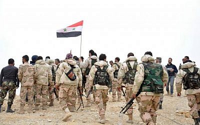 File: Syrian soldiers gather around a Syrian national flag in Palmyra, Syria, after taking the city from Islamic State, March 27, 2016. (SANA via AP)