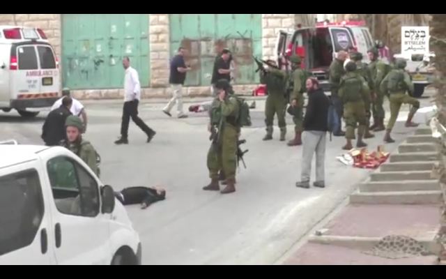 An IDF soldier loading his weapon before he appears to shoot an apparently unarmed, prone Palestinian assailant in the head following a stabbing attack in Hebron on March 24, 2016. (Screen capture: B'Tselem)