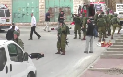 An IDF soldier loading his weapon before he appears to shoot an unarmed, prone Palestinian assailant in the head following a stabbing attack in Hebron on March 24, 2016. (Screen capture: B'Tselem)