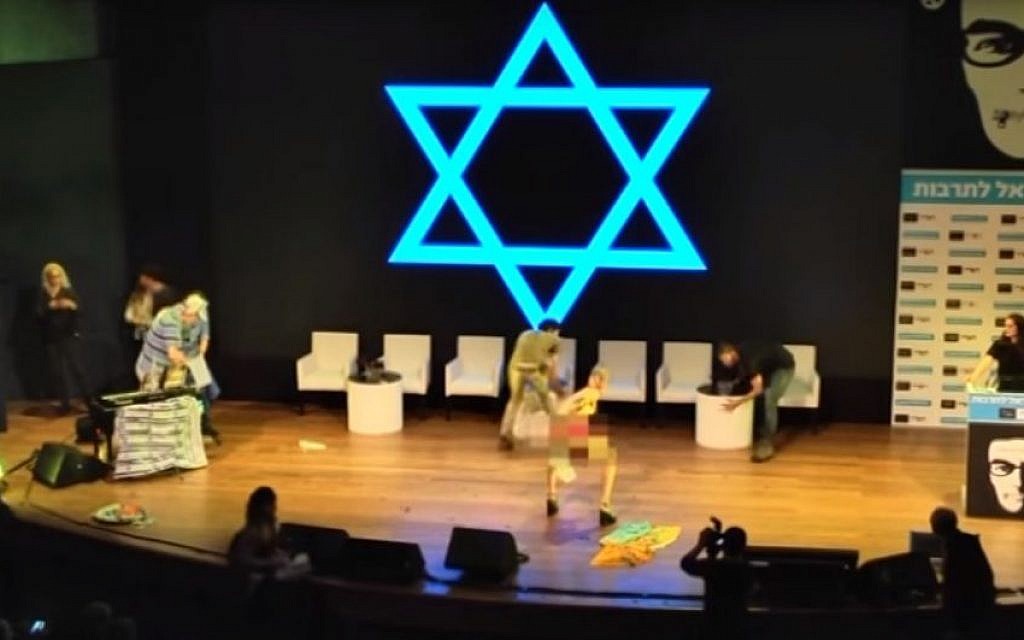 Artist Ariel Bronz getting personal with a flag at a Haaretz conference in Tel Aviv on March 6, 2016. (Screen capture: YouTube/Haaretz)