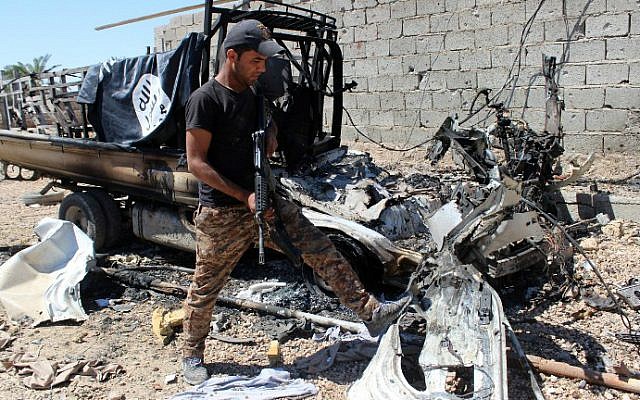 A member of Iraqi government forces inspects a burnt vehicle with a flag of the Islamic State (IS) on its top after they retook an area from jihadists on April 2, 2016 in the village of Al-Mamoura, near Hit, a Euphrates Valley town located about 145 kilometers west of Baghdad in the western province of Anbar. (Moadh al-Dulaimi/AFP)