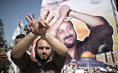 A Palestinian man gestures in front of a poster bearing the portrait of jailed Fatah leader Marwan Barghouti, during a rally marking Palestinian Prisoner Day in Gaza City on April 17, 2016. (AFP PHOTO/MAHMUD HAMS)