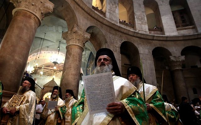 Greek Orthodox priests hold palm branches as they circle the aedicule during the Palm Sunday Easter procession at the Church of the Holy Sepulchre in Jerusalem's Old City on April 24, 2016 (AFP/Gali Tibbon)