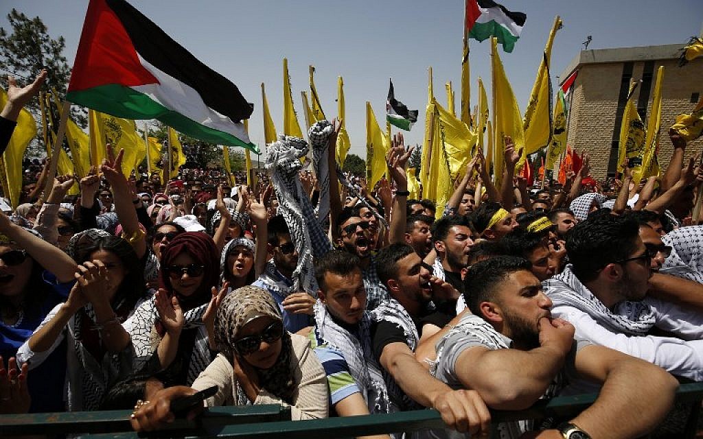 Palestinian students supporting the Fatah movement wave both their national and the movement's flag during an election campaign rally for the student council at Birzeit University, near the West Bank city of Ramallah on April 26, 2016 / AFP PHOTO / ABBAS MOMANI