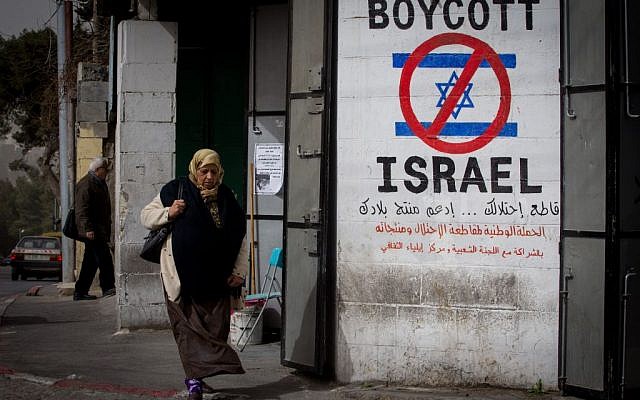 A Palestinian woman walks by a sign calling for a boycott of Israel in the West Bank city of Bethlehem on February 11, 2015. (Miriam Alster/Flash 90)