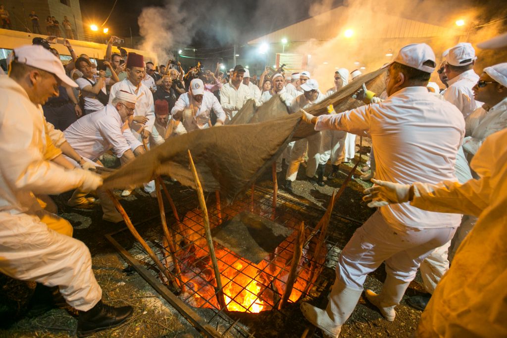 Samaritan priests insert their skewered Passover sacrifices into an underground oven during the ritual of sacrifice, part of a Samaritan Passover ceremony, on Mount Grizim, near the West Bank town of Nablus, April 20, 2016. (Yaniv Nadav/FLASH90)