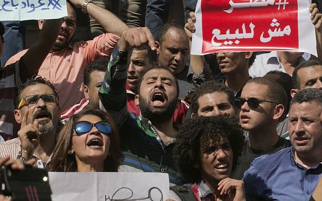 Egyptians shout slogans against Egyptian President Abdel-Fattah el-Sissi during a protest against the decision to hand over control of two strategic Red Sea islands to Saudi Arabia in front of the Press Syndicate, in Cairo, Egypt, Friday, April 15, 2016. Arabic reads, "Awad sold his land" and "Egypt is not for sale." (AP Photo/Amr Nabil) 