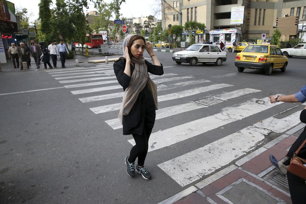 An Iranian woman adjusts her head scarf while crossing a street in downtown Tehran, Iran, Tuesday, April 26, 2016. (AP Photo/Vahid Salemi)